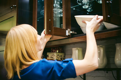 Woman taking bowl from kitchen cabinet