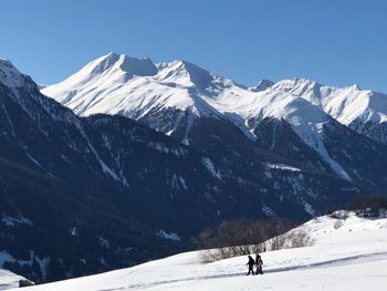 People walking against snowcapped mountains