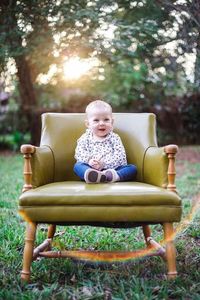 Portrait of happy boy sitting on sofa in park