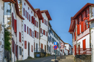 Road sign by buildings against sky in city