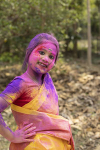 A pretty indian bengali girl child in saree and colorful face during holi