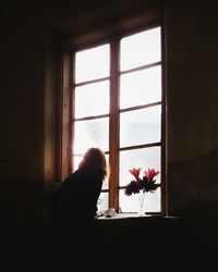 Rear view of woman looking through window