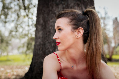 Close-up of woman against tree trunk on land 