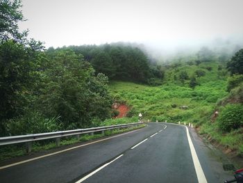 Road amidst trees against clear sky