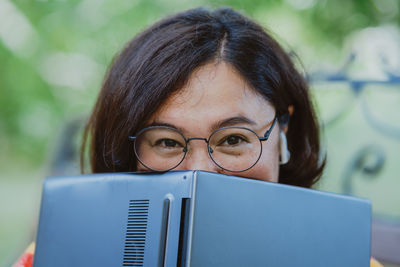 Woman using her laptop as an open book, covering her face