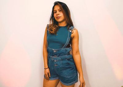 Portrait of a beautiful young woman standing against wall