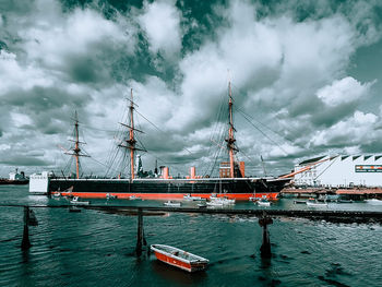 Sailboats moored at harbor against sky