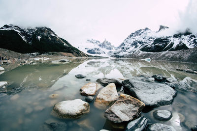 Glacial lake with snowcapped mountains in the background in winter