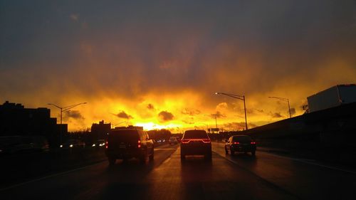 Cars on road against sky at sunset