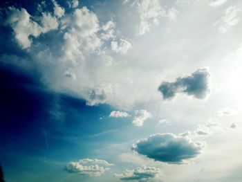 Low angle view of sunlight streaming through clouds