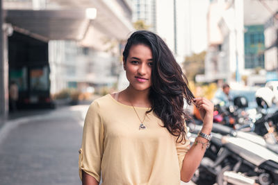 Portrait of young woman standing on street in city