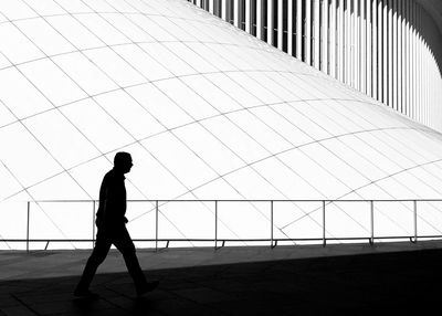 Silhouette man walking on modern building against sky in city