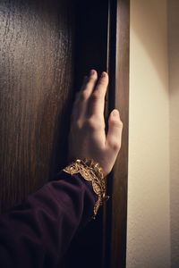 Close-up of hand holding metal against wall at home