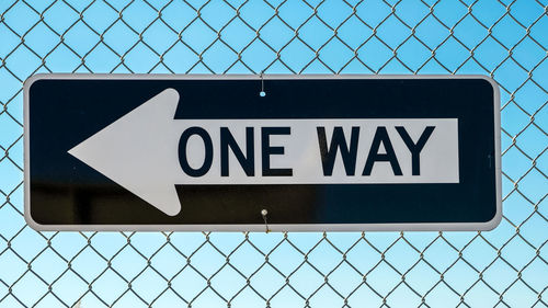 Close-up of information sign on chainlink fence