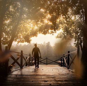 Rear view of men on footbridge against sky