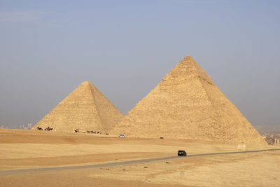 Scenic view of desert and pyramids against clear sky