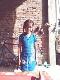 Portrait of smiling girl against brick wall