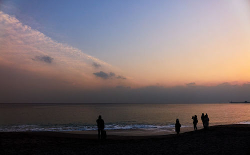 Silhouette people at beach against sky during sunset