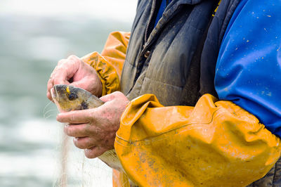 Midsection of fisherman holding fish