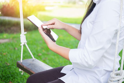 Midsection of man using mobile phone in grass