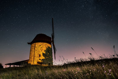 Low angle view of windmill on field against sky at night