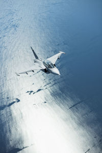 High angle view of airplane flying over sea against sky