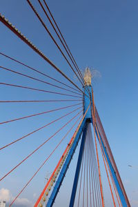 Low angle view of bridge cables against clear blue sky