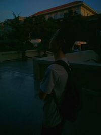 Rear view of man standing outside house at night