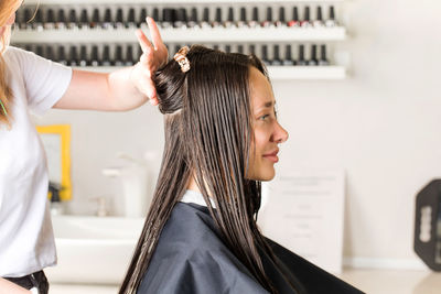 The hairdresser makes a haircut to the client in a beauty salon.