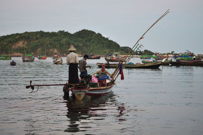 People on boat in river against sky