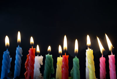 Close-up of illuminated candles against black background