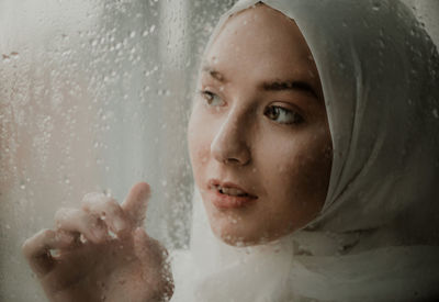 Close-up of woman by wet glass