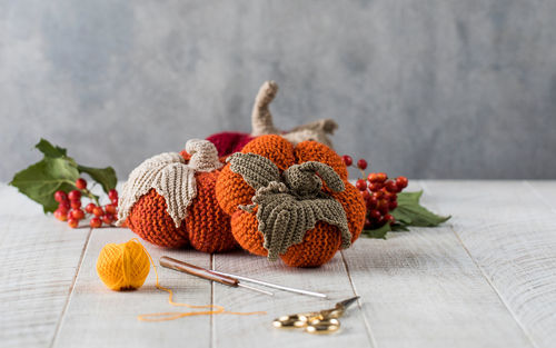 Knitted pumpkins with leaves crochets and scissors on table