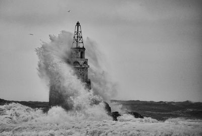 Water from sea splashing on lighthouse against sky