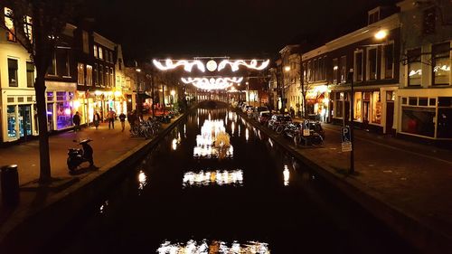 People in illuminated city against sky at night