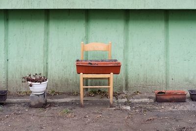 Empty chairs and plants against wall