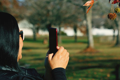 Close-up of woman photographing with smart phone in park
