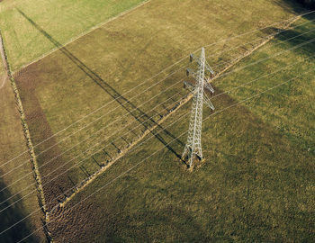 Power pole with strong shadow on a green field