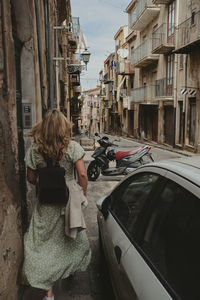 Rear view of woman sitting on street in city