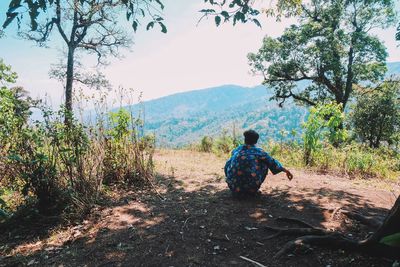 Rear view of man sitting on land