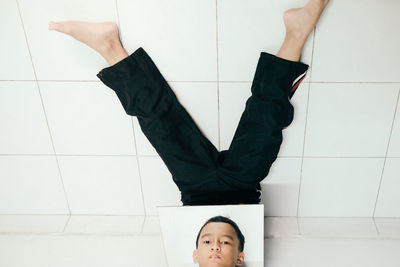 Portrait of boy doing magic trick against tiled wall