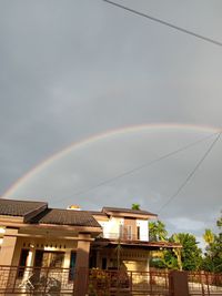 Low angle view of rainbow over buildings against sky