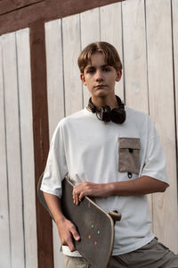 Portrait of young man standing against wall