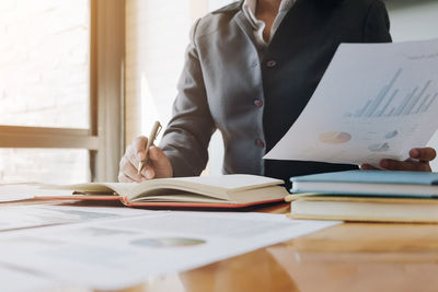 Midsection of woman reading book on table