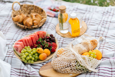 Fresh fruits and drinks on a picnic blanket.