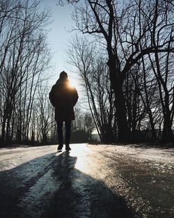 Rear view of silhouette man walking on road