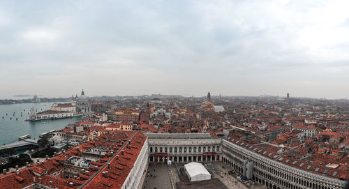 High angle view of buildings in city against cloudy sky