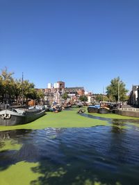 Boats moored in river in city against clear sky