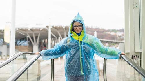 Portrait of smiling young woman standing against railing