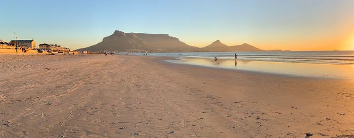 Scenic view of beach against clear sky during sunset